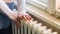 Girl in a wool sweater puts hands on an older radiator. (Picture: ©Zvone/Shutterstock.com)