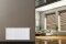 Vitoset universal radiator, living room in the background with shaded windows, sofa, plants and yucca palms..